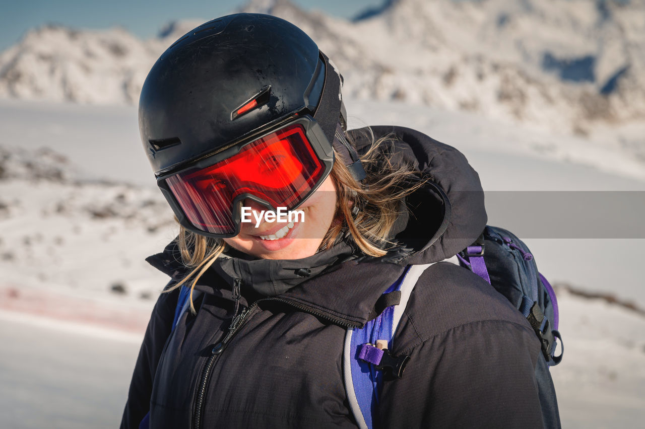 Skier smiling happy cheerful satisfied woman in warm windbreaker jacket ski goggles mask glasses