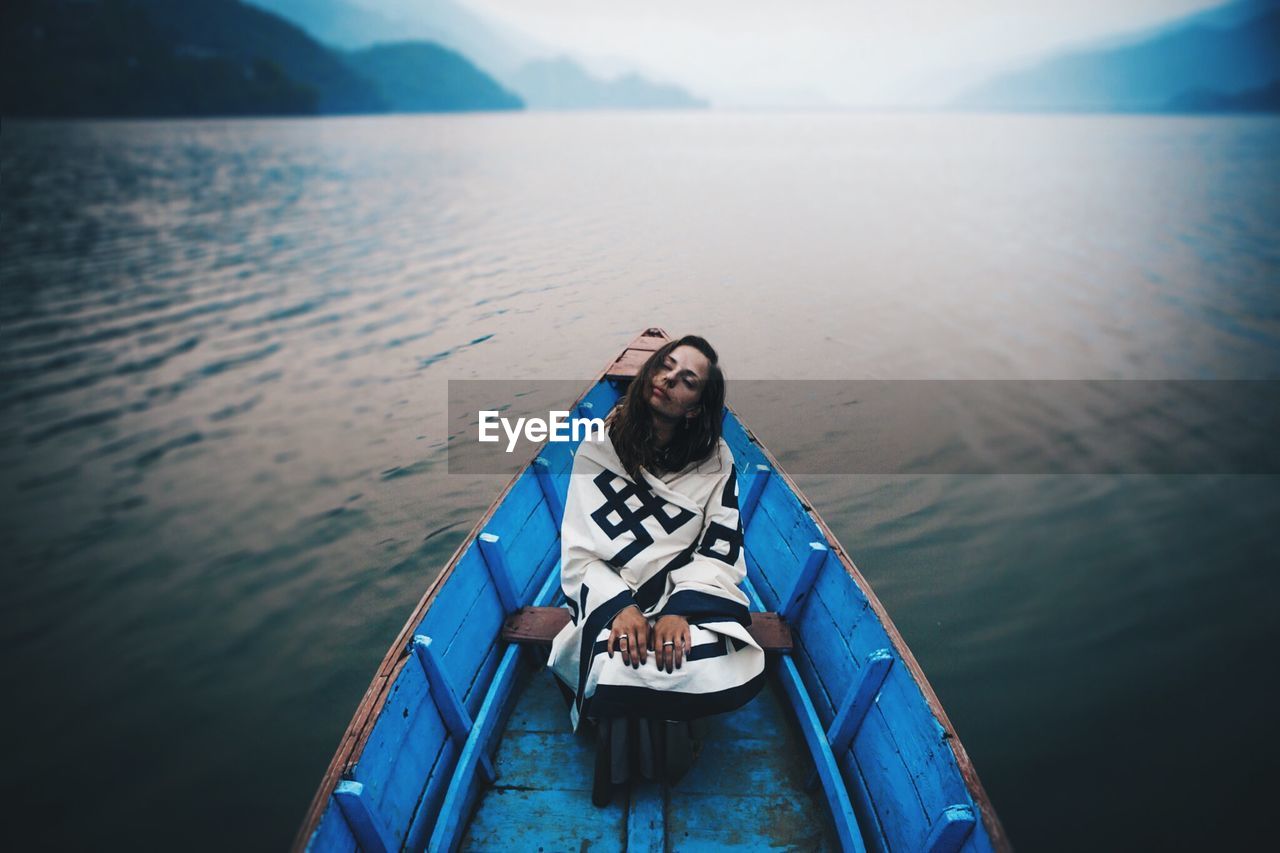 Full length of woman sailing in blue rowboat in river