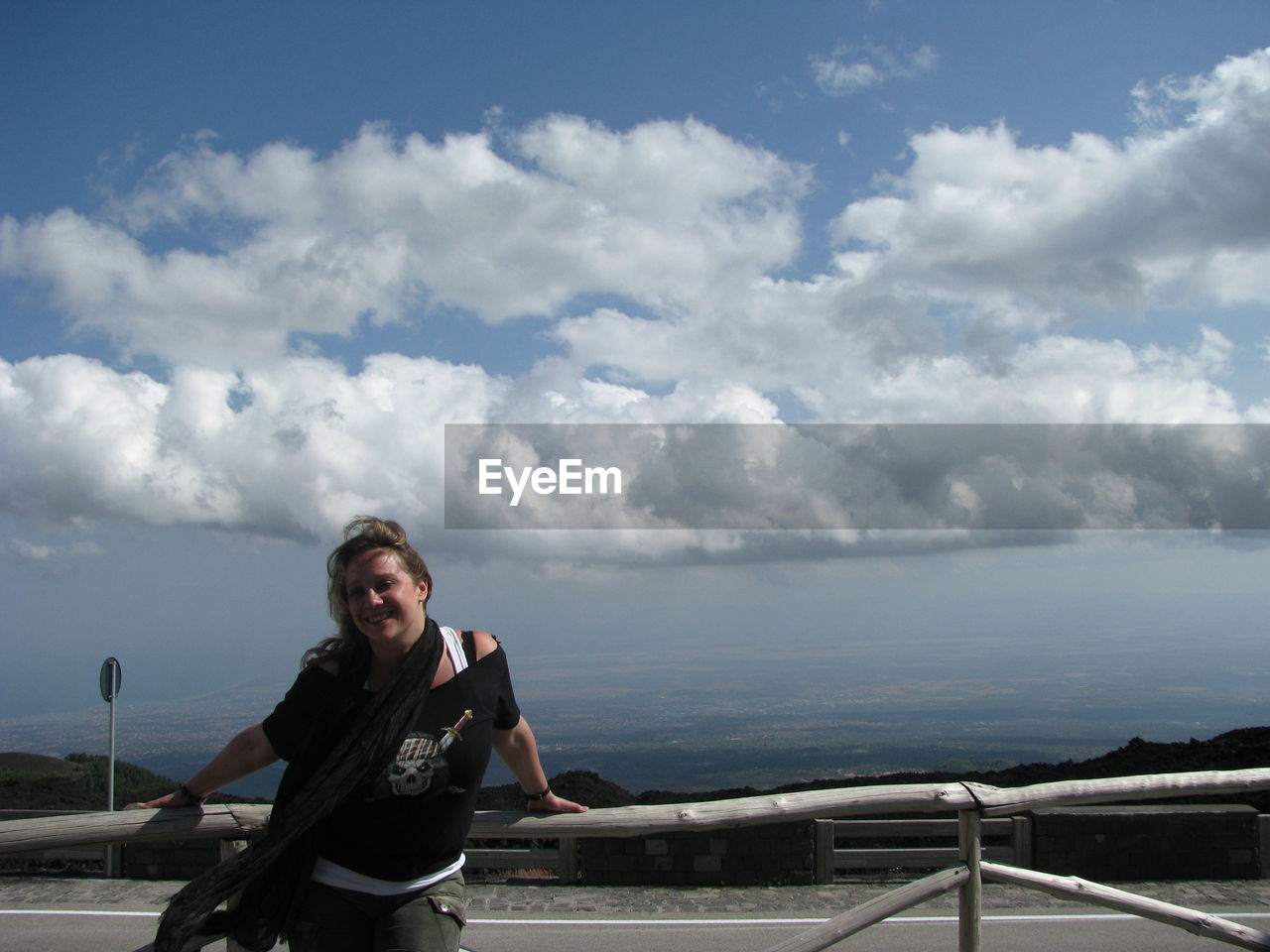 Smiling young woman standing by railing