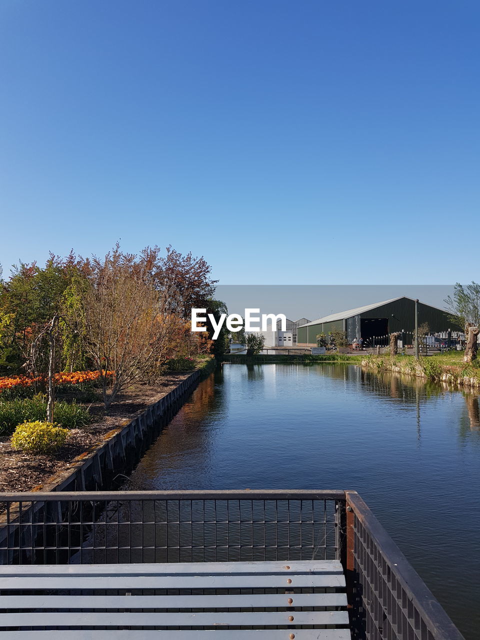 Scenic view of canal  against clear blue sky