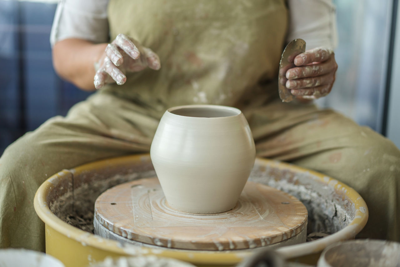 Midsection of woman making pottery in workshop