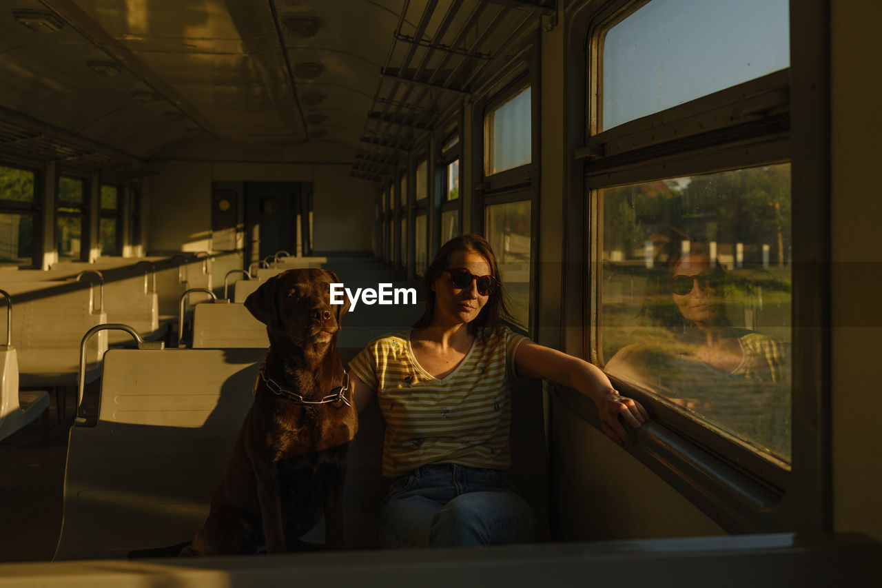 Woman and retriever dog ride a train, look out the window. traveling with a pet on public transport