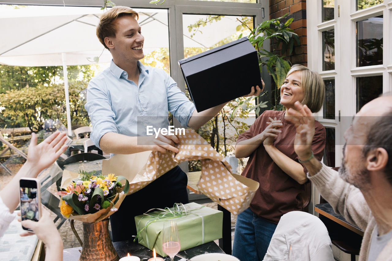 Happy man holding shoe box during birthday party at restaurant