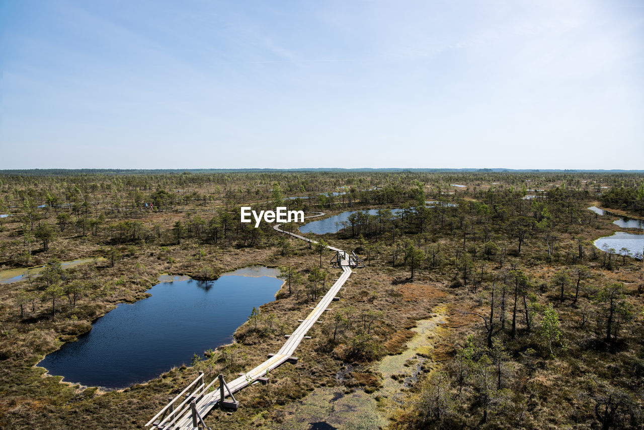 Scenic view of ponds and landscape against sky