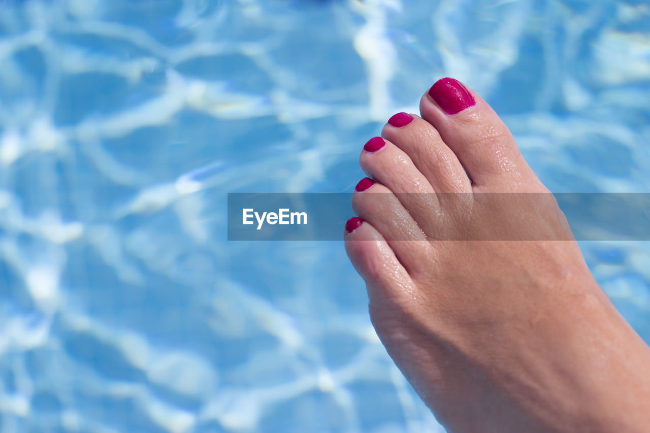 Low section of woman relaxing in swimming pool