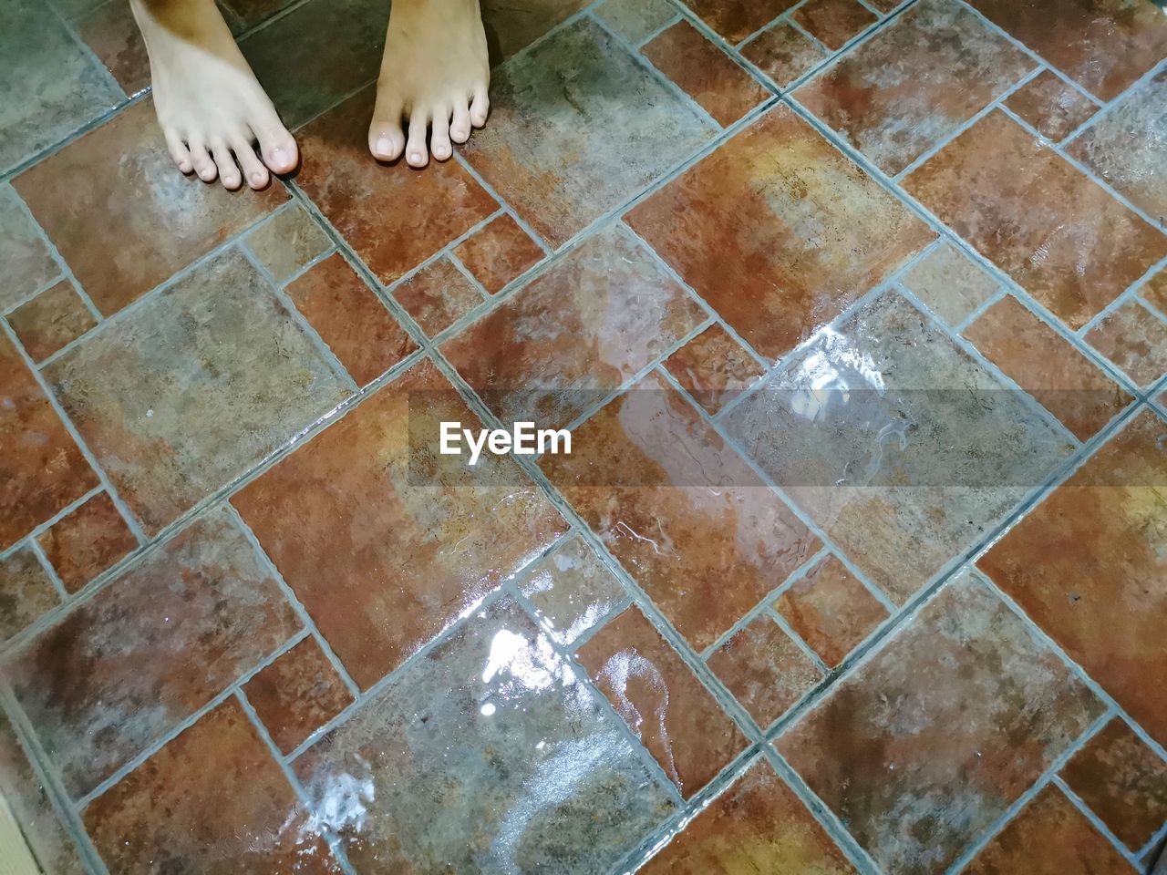 LOW SECTION OF WOMAN STANDING ON TILED FLOOR