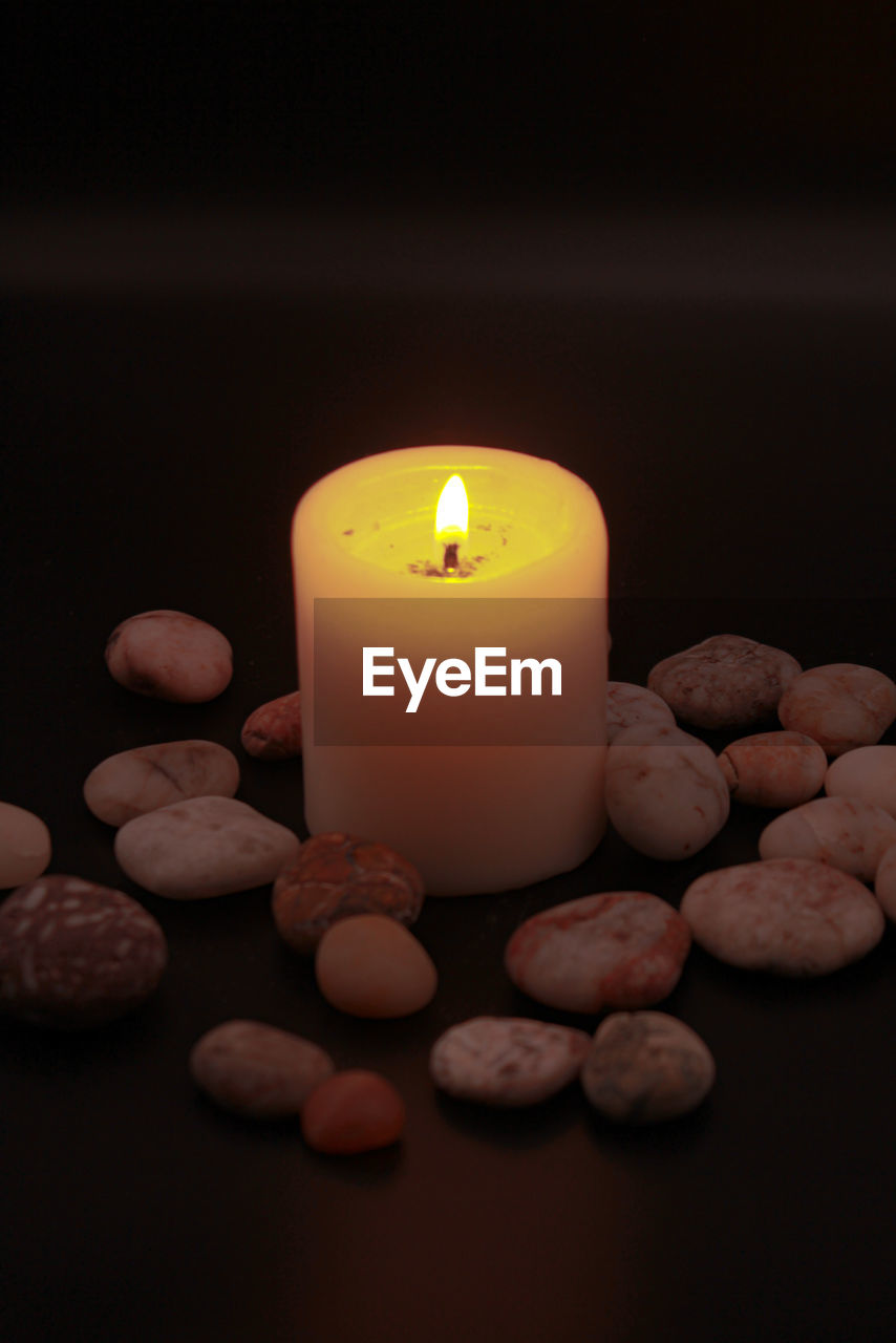 CLOSE-UP OF ILLUMINATED CANDLES ON TABLE