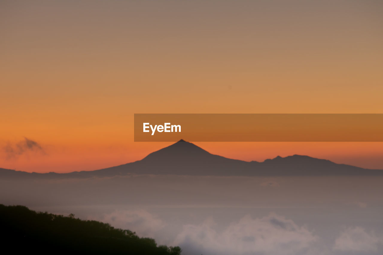 Scenic view of silhouette mountains against orange sky