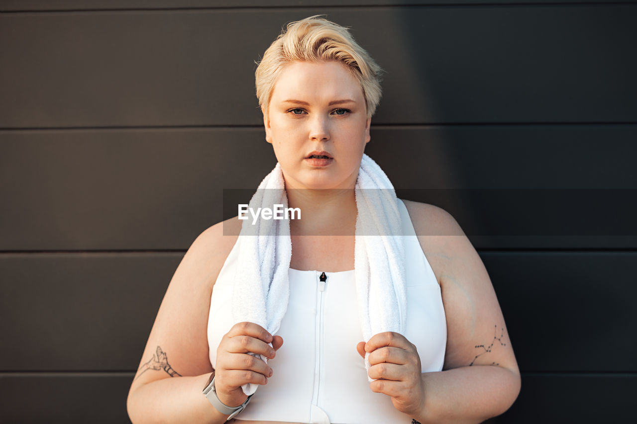 Portrait of beautiful young woman standing against wall