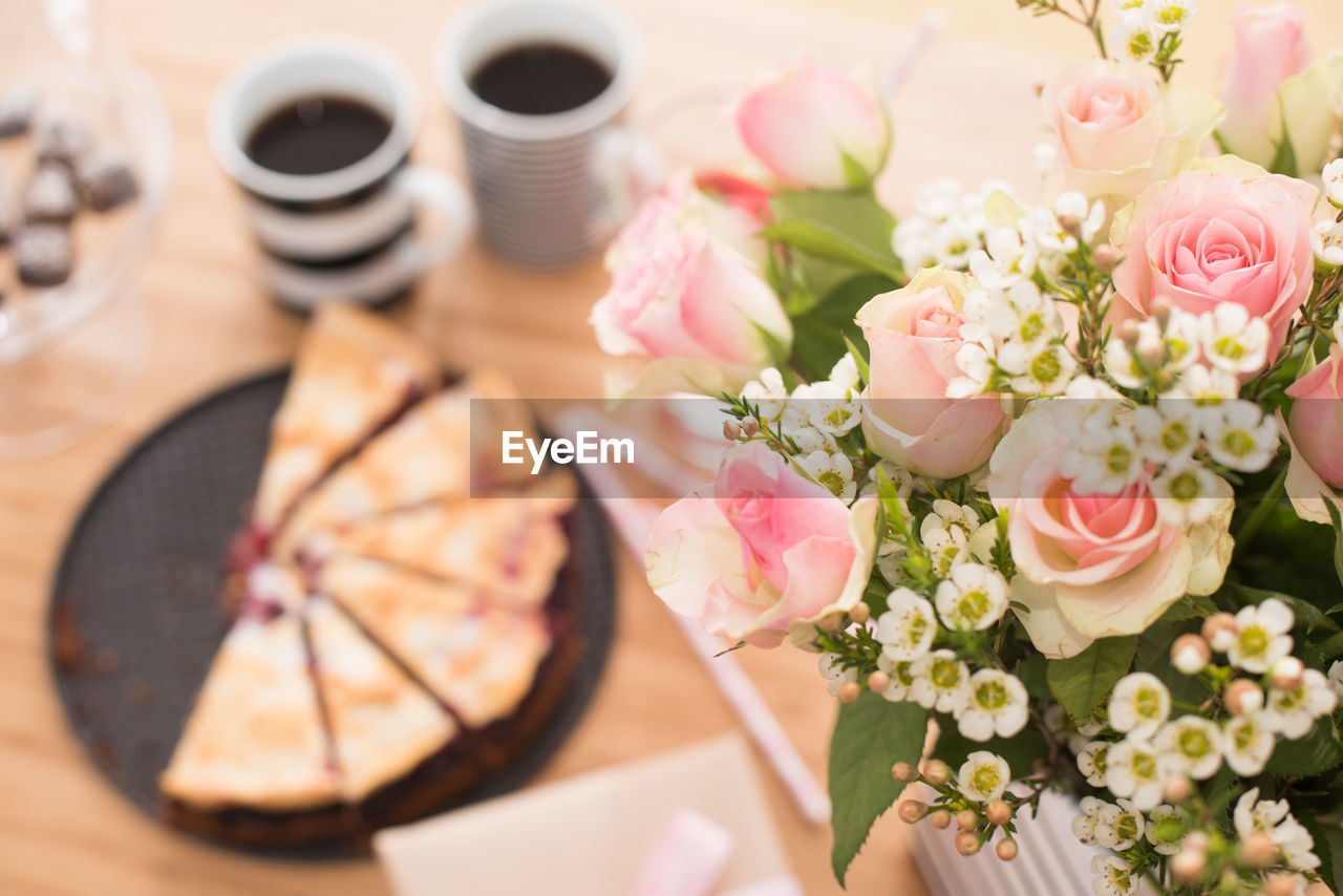 High angle view of flowers by gift with drink on table at home