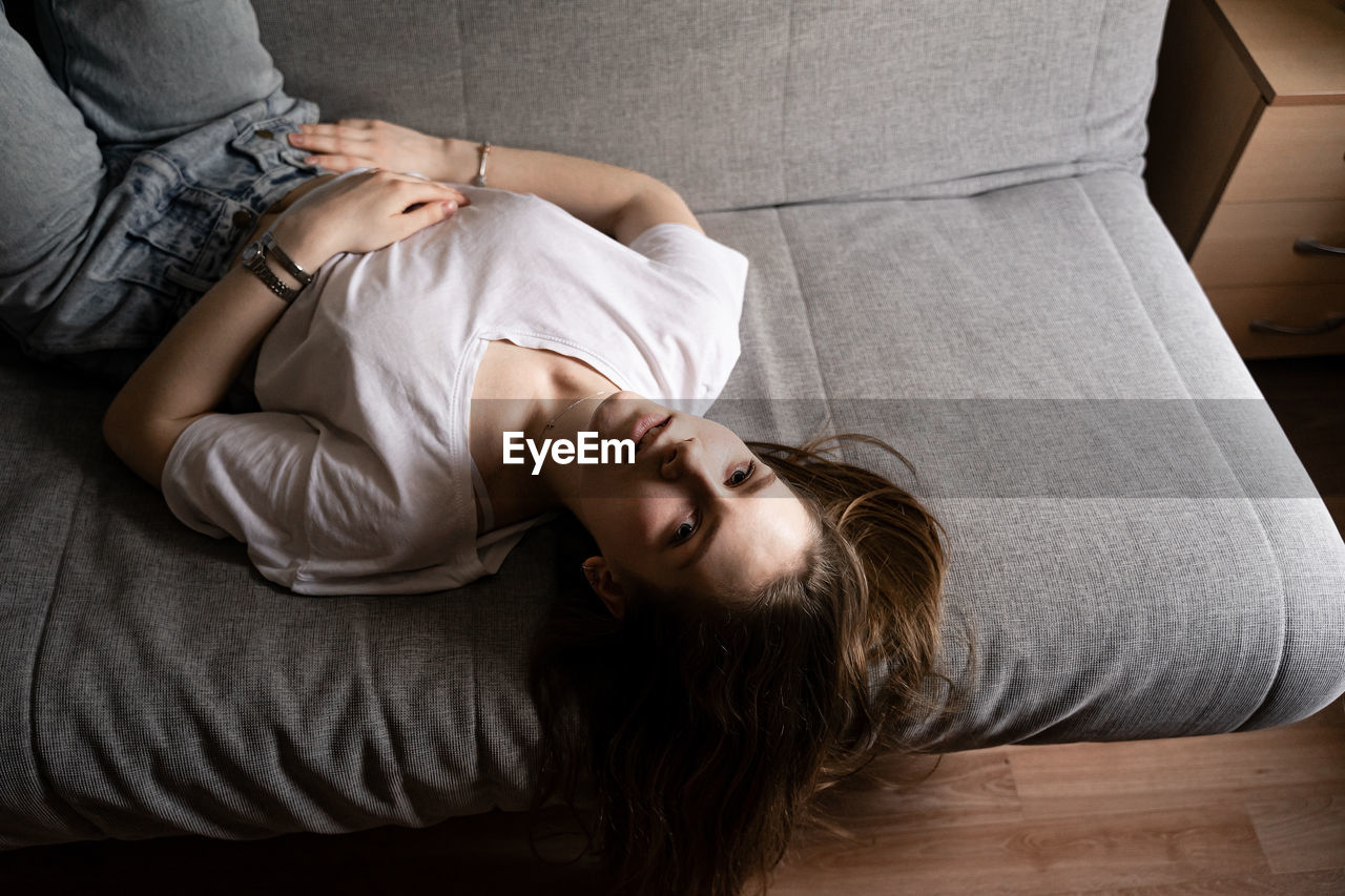 High angle portrait of woman lying on sofa at home