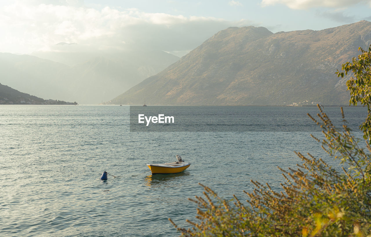 water, mountain, nautical vessel, scenics - nature, transportation, nature, beauty in nature, lake, sky, travel, environment, mode of transportation, landscape, mountain range, cloud, bay, tranquility, shore, tranquil scene, travel destinations, land, leisure activity, plant, day, outdoors, vacation, trip, coast, adventure, holiday, tourism, wilderness, activity, reservoir, fog, non-urban scene, beach, boating, vehicle, boat, idyllic, sunlight, body of water, morning, no people