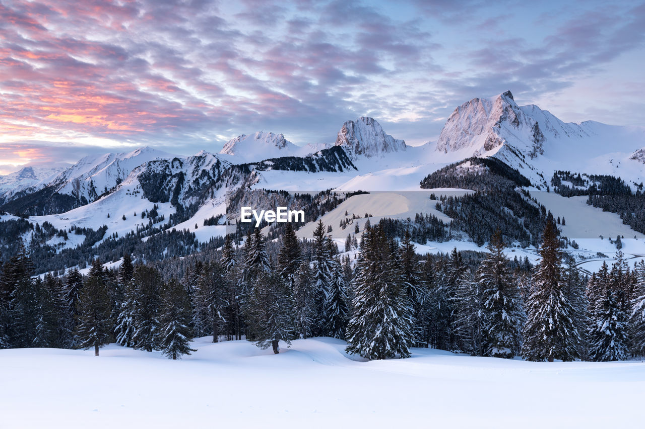 Scenic view of snow covered landscape and mountains against sky during sunset