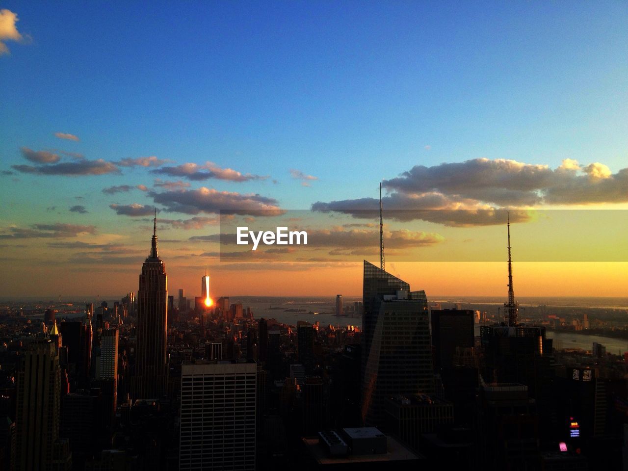 Skyscrapers amidst buildings against blue sky during sunset