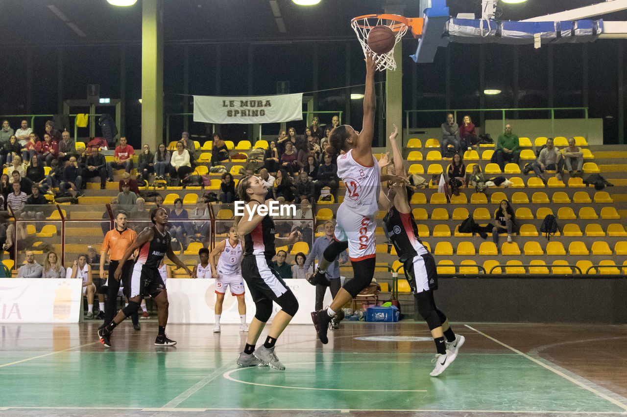 GROUP OF PEOPLE PLAYING BASKETBALL IN COURT