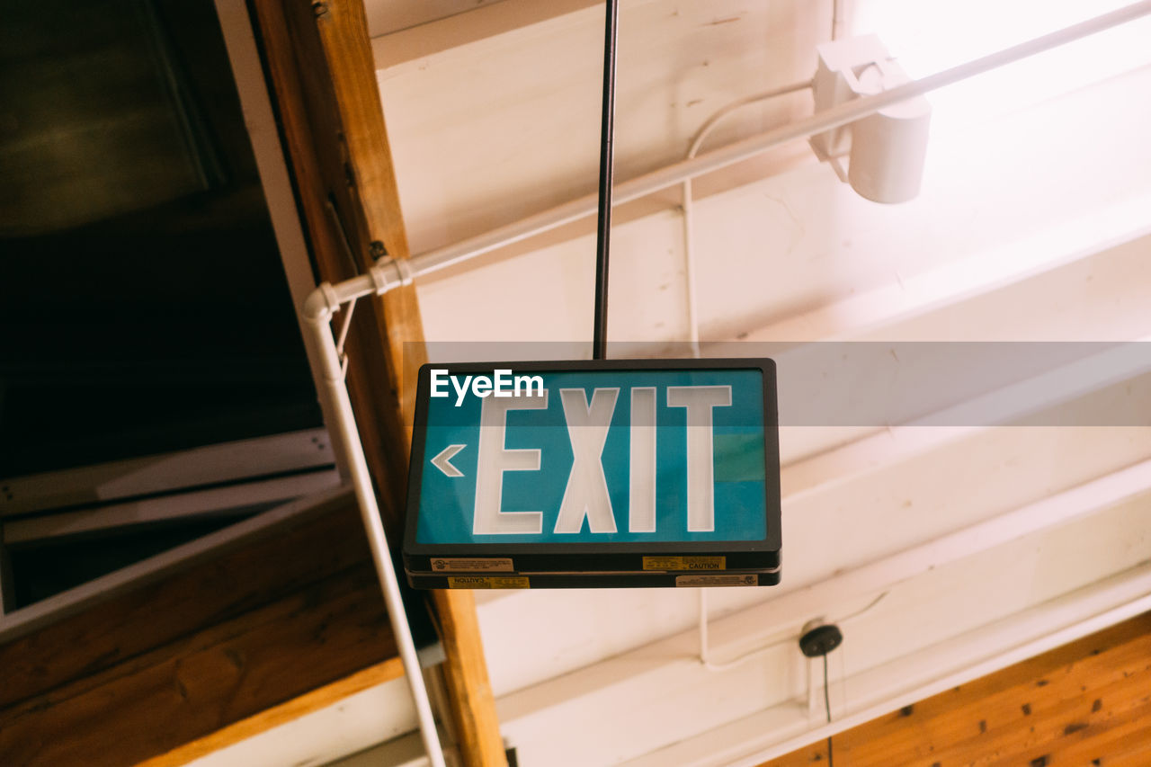 Low angle view of exit sign hanging from ceiling