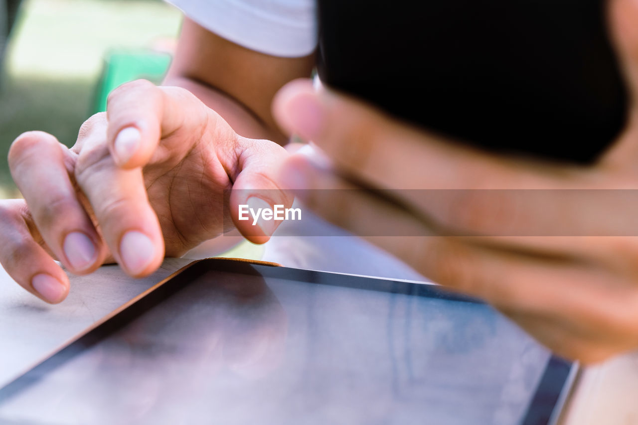 Close up image of a man using mobile smart phone and digital tablet