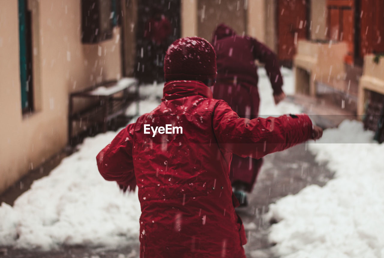 Rear view of people running on street during winter