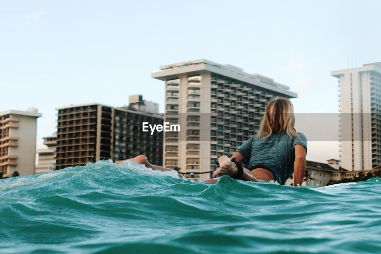 Low angle view of woman swimming in sea against buildings