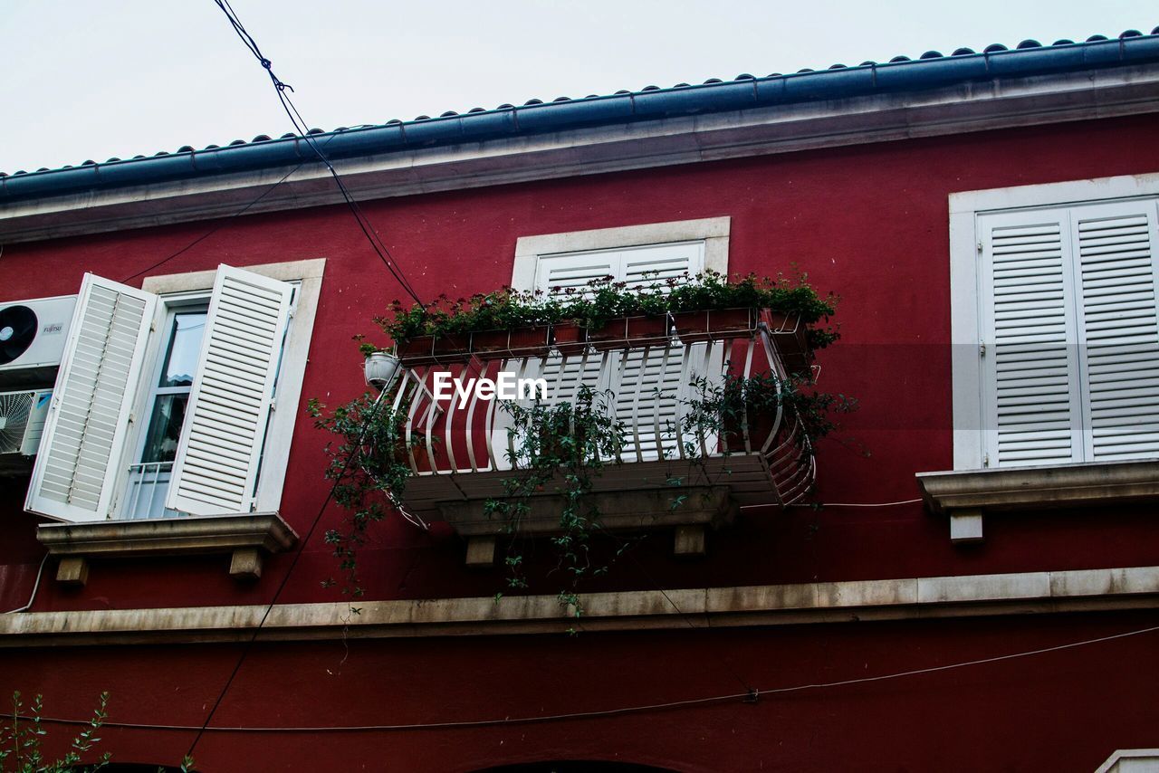 LOW ANGLE VIEW OF RED HOUSE WINDOW