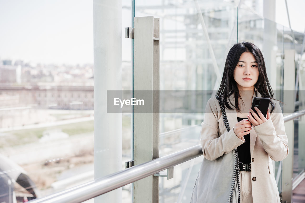 Portrait of beautiful chinese business woman using mobile phone in building office. technology