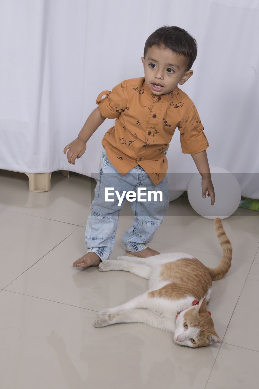 Portrait of a boy with cat on floor at home