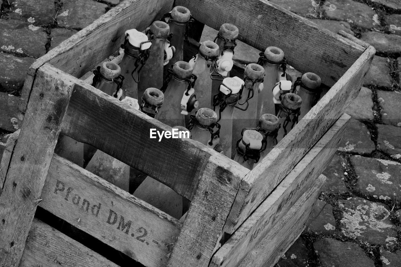 High angle view of old bottles in wooden box on footpath