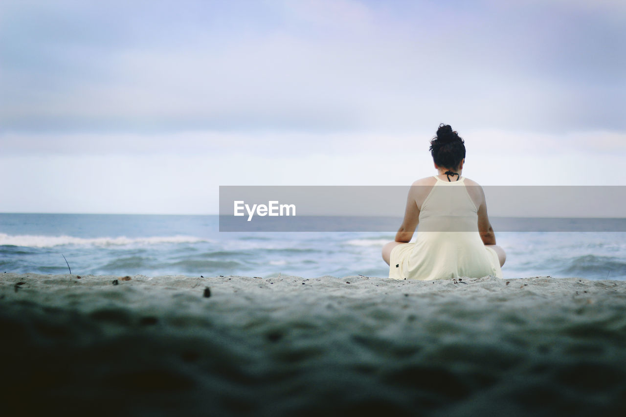 Rear view of woman sitting on beach