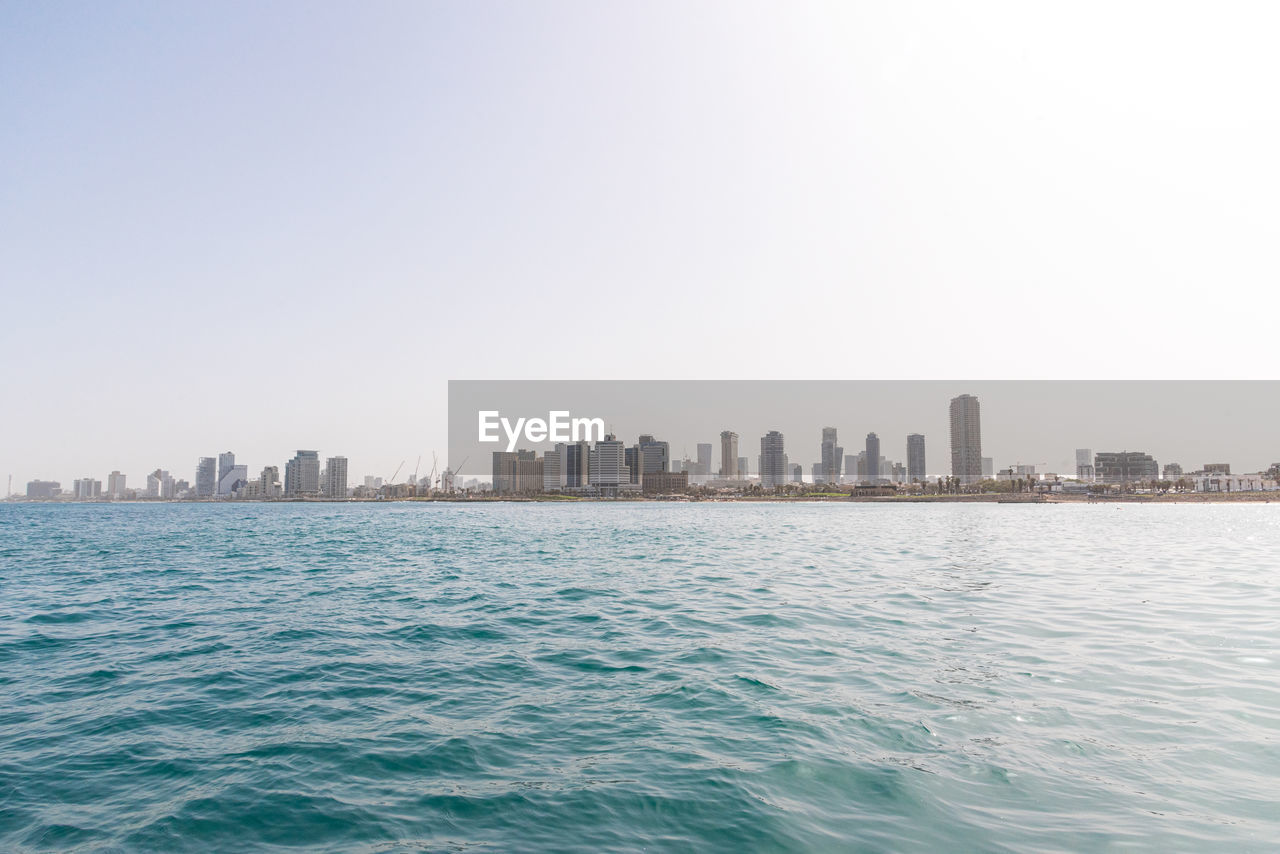 scenic view of sea by buildings against clear sky