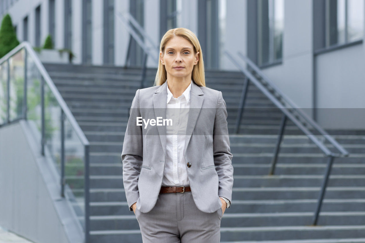 portrait of young businesswoman standing against building