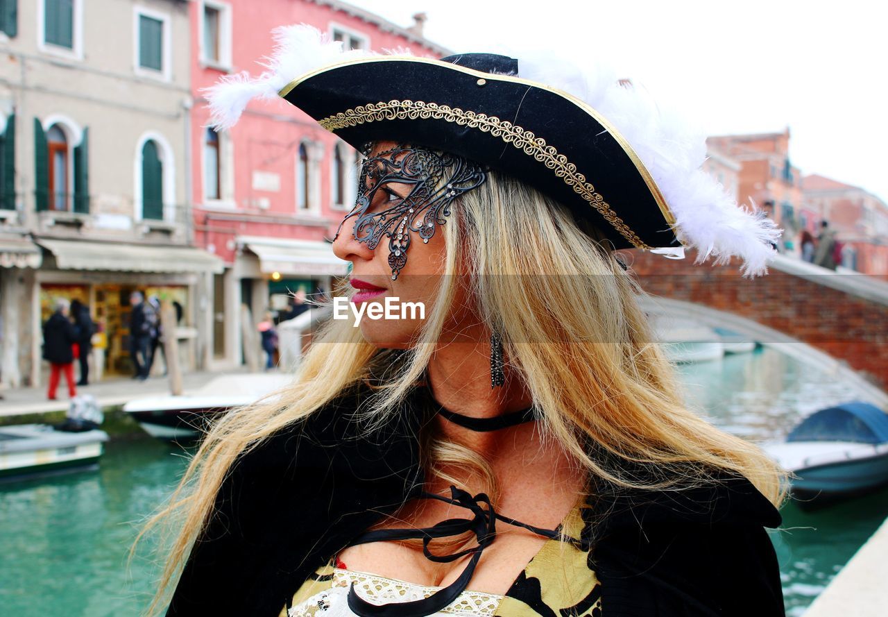 Woman venetian mask standing by canal