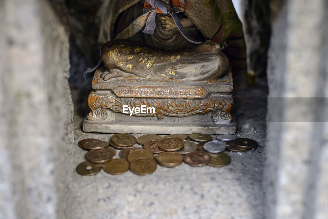 Close-up of coins by statue in temple