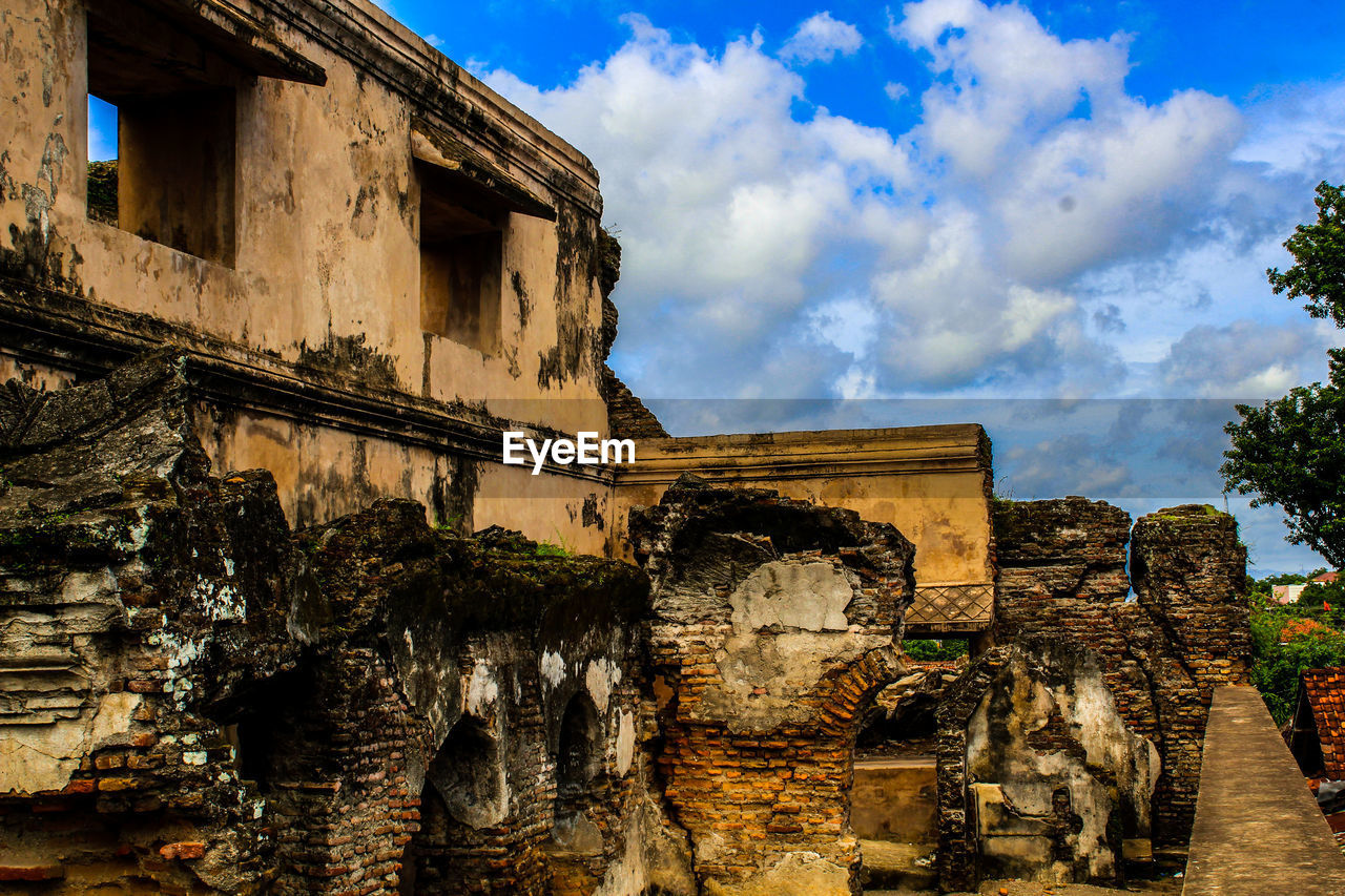 LOW ANGLE VIEW OF OLD BUILDINGS AGAINST CLOUDY SKY