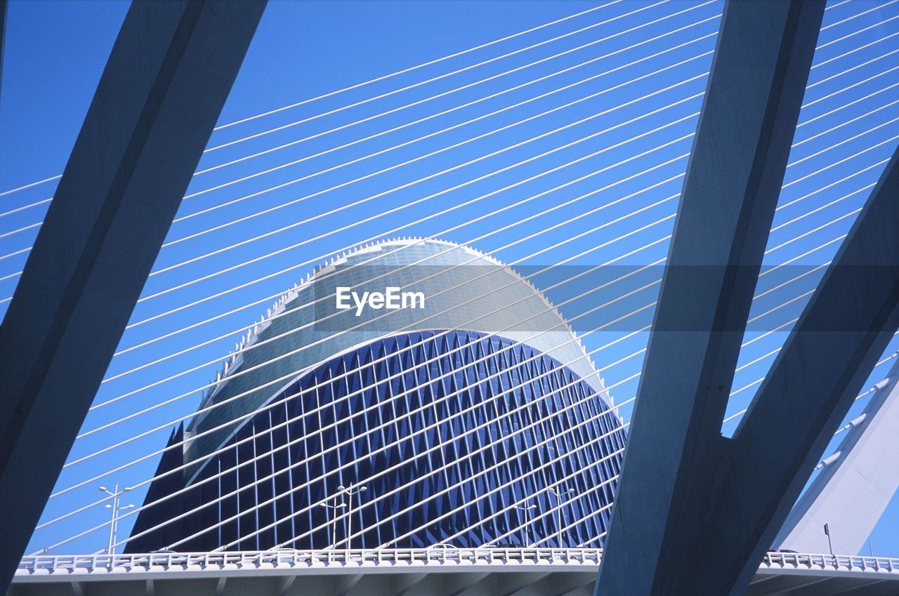 LOW ANGLE VIEW OF ELECTRICITY PYLON AGAINST MODERN BUILDING