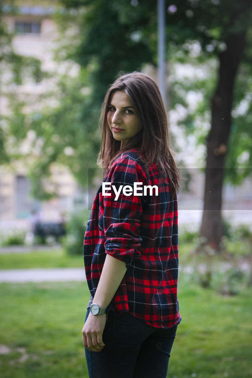 Portrait of beautiful young woman standing at park