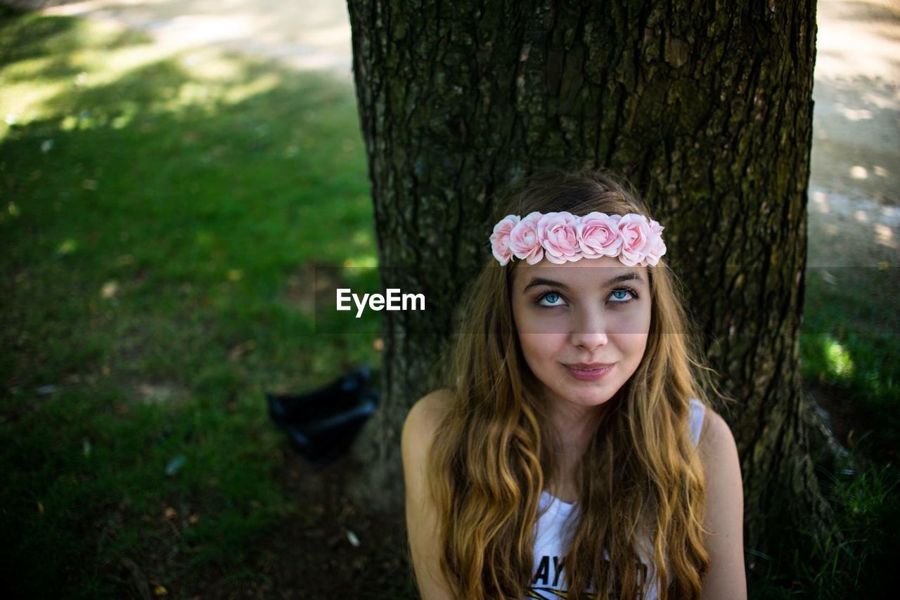 High angle portrait of woman wearing wreath against tree trunk