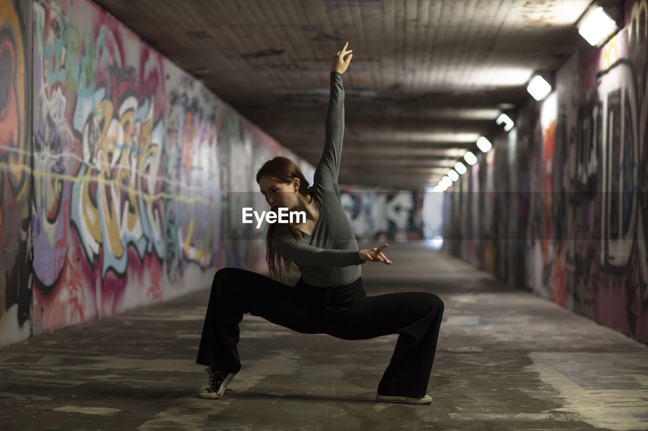 Full length of woman dancing in illuminated tunnel