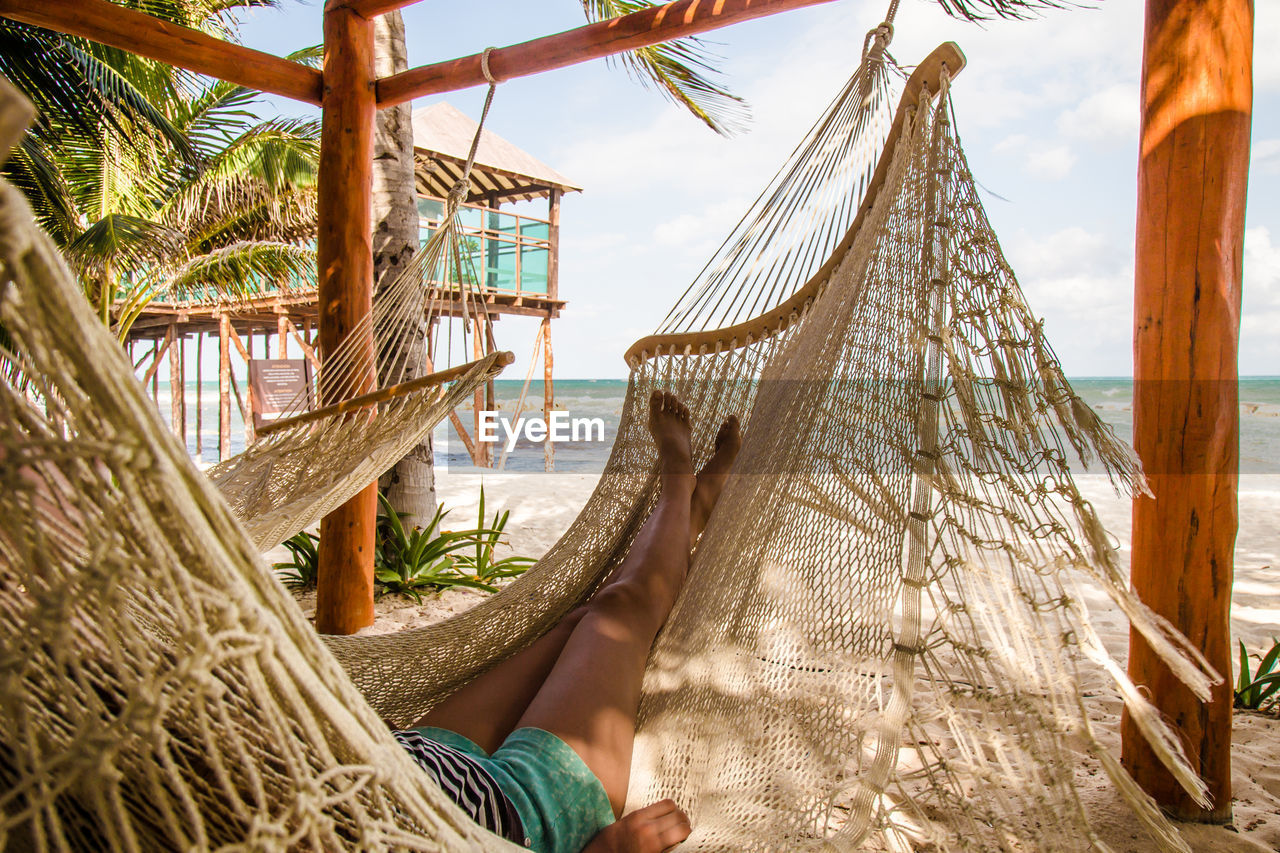 Bare legs and feet of a young girl lounging in a hammock at a beach at the riviera maya, mexico