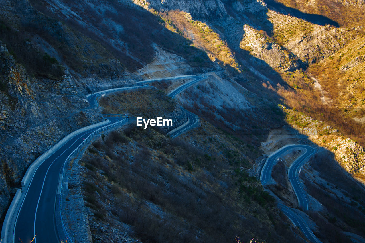 HIGH ANGLE VIEW OF WINDING ROAD ON MOUNTAINS