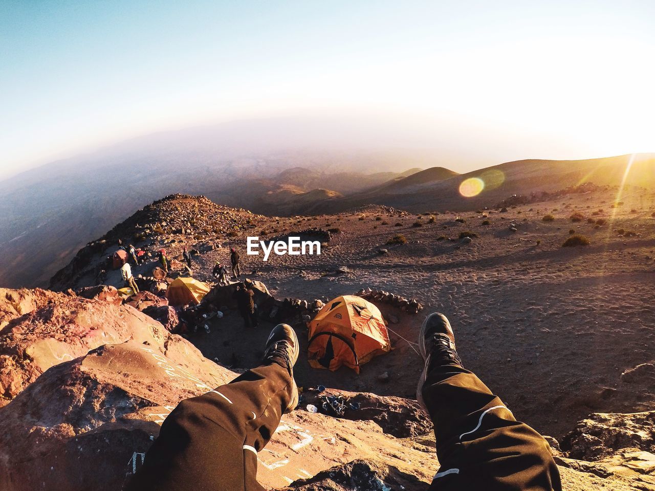 PEOPLE ON ROCKS AGAINST SKY DURING SUNRISE