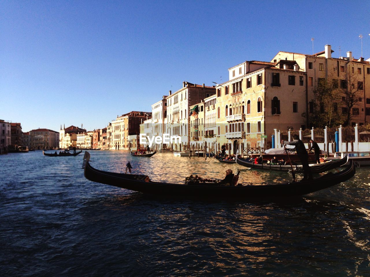 BOATS IN CANAL AMIDST BUILDINGS IN CITY