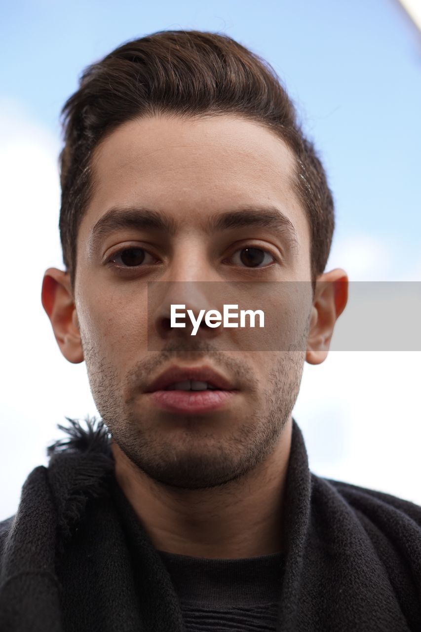 Close-up portrait of young man against sky