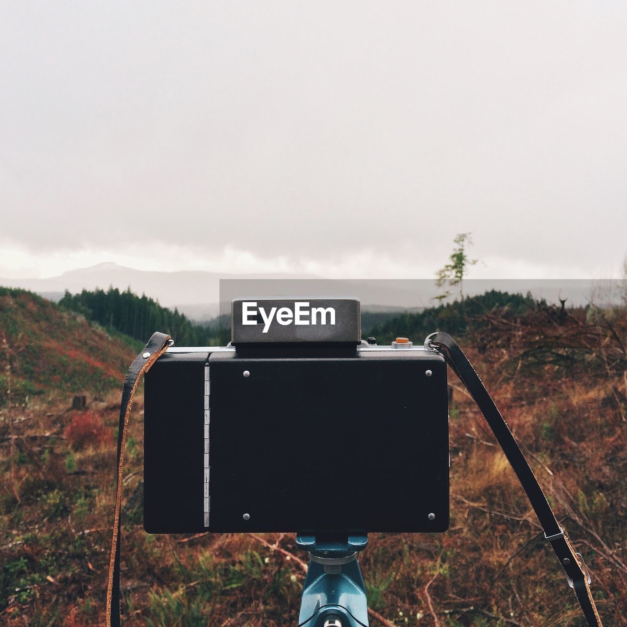 Close-up of camera in front of mountains against cloudy sky