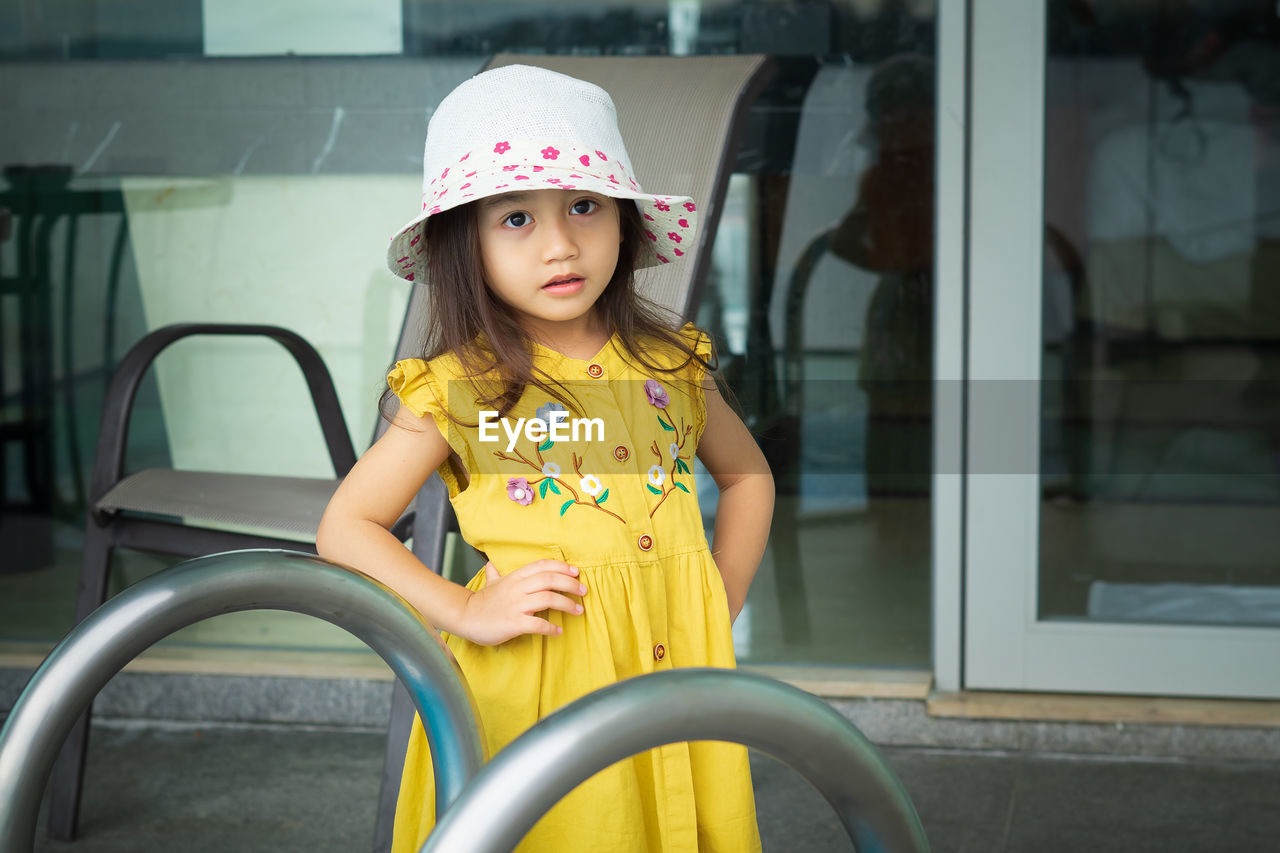 Beautiful little gorgeus lovely toddler girl in mustard summer look clothes, fashion dress, and hat.