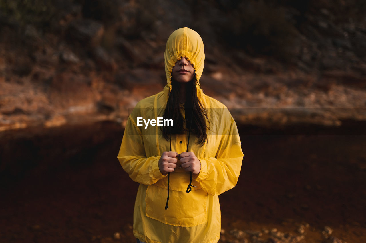 Young lady in yellow raincoat strolling in nature