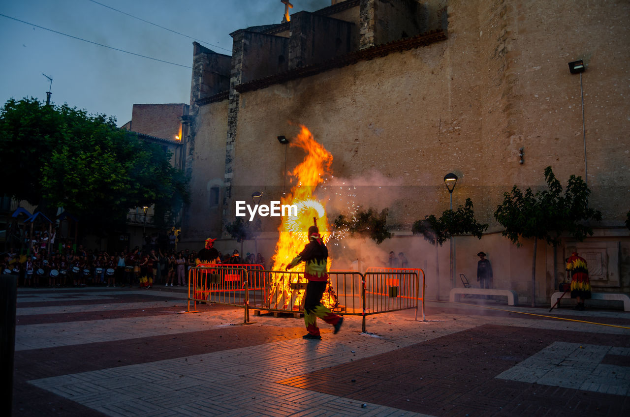 fire, burning, architecture, flame, building exterior, city, street, night, heat, nature, built structure, sign, evening, building, accidents and disasters, outdoors, communication, adult, tree, men