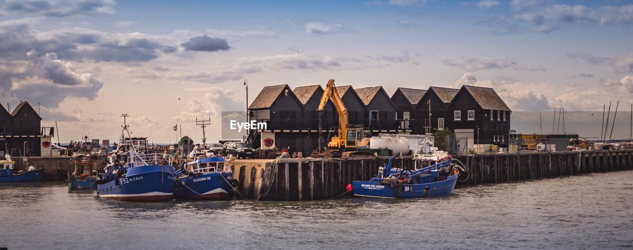 BOATS MOORED ON RIVER BY BUILDINGS AGAINST SKY