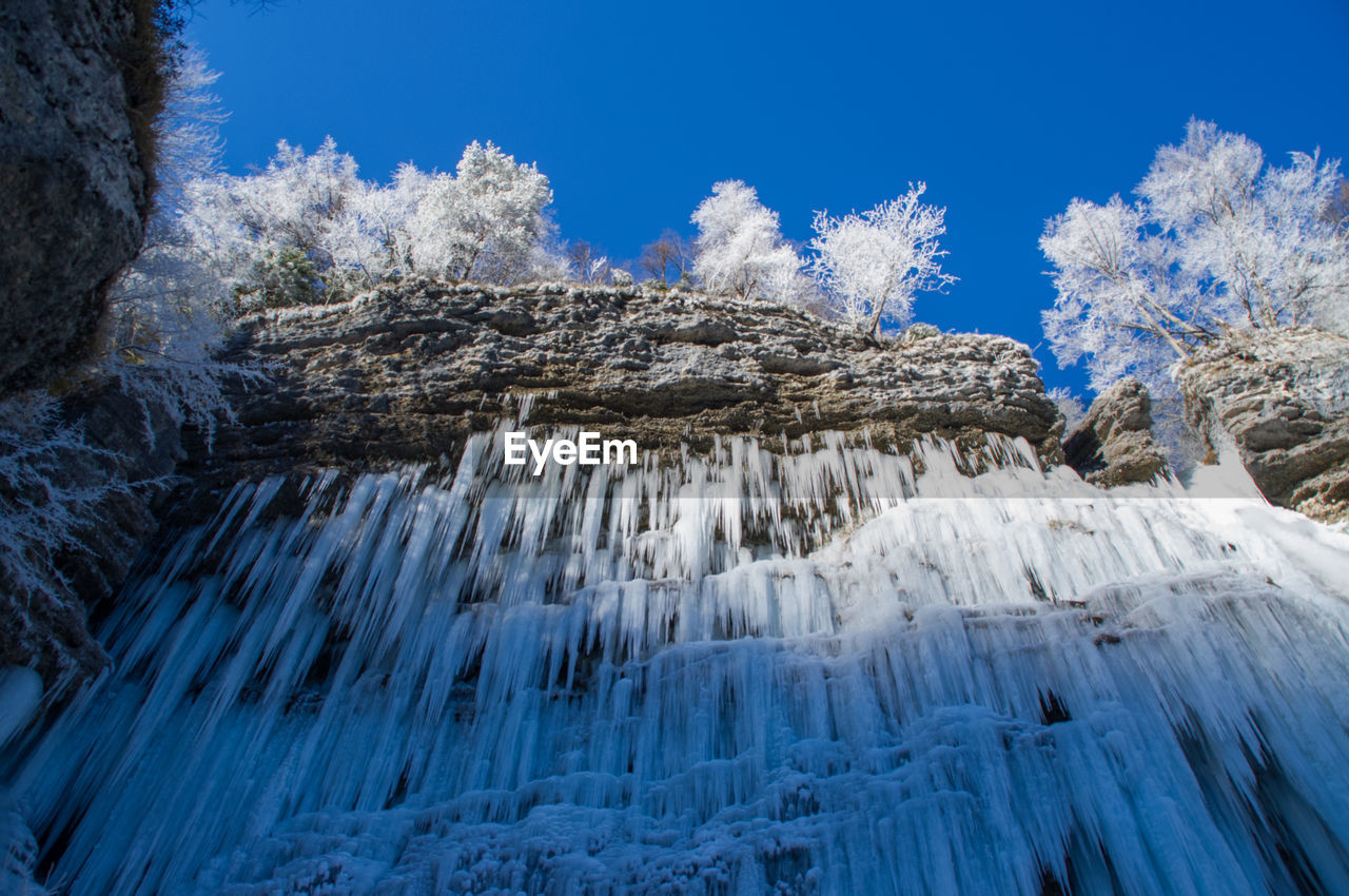 Low angle view of icicles against blue sky