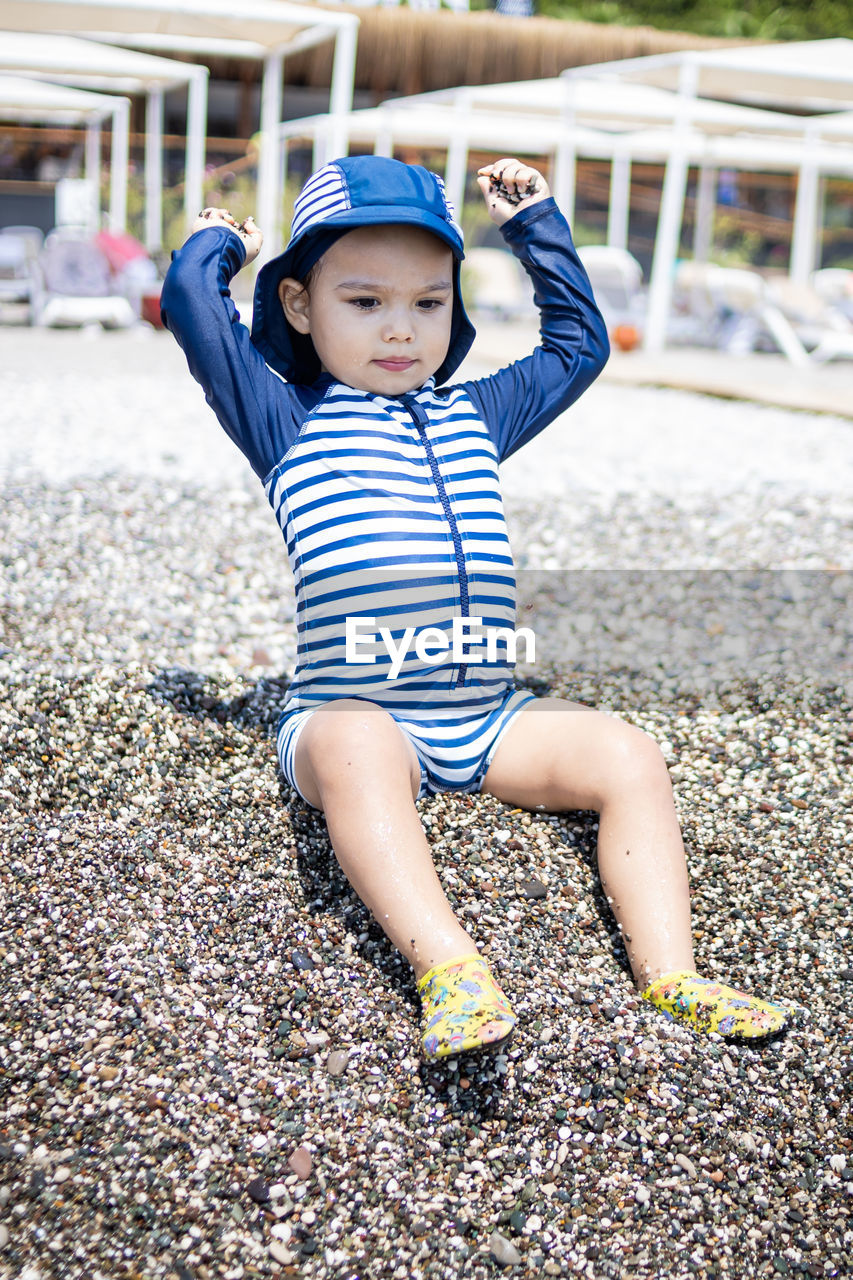 childhood, child, one person, men, full length, striped, blue, toddler, innocence, casual clothing, fun, spring, cute, happiness, playground, day, emotion, smiling, clothing, person, front view, portrait, leisure activity, nature, outdoors, baby, looking at camera, enjoyment, human face, lifestyles, sitting, looking, architecture, hat