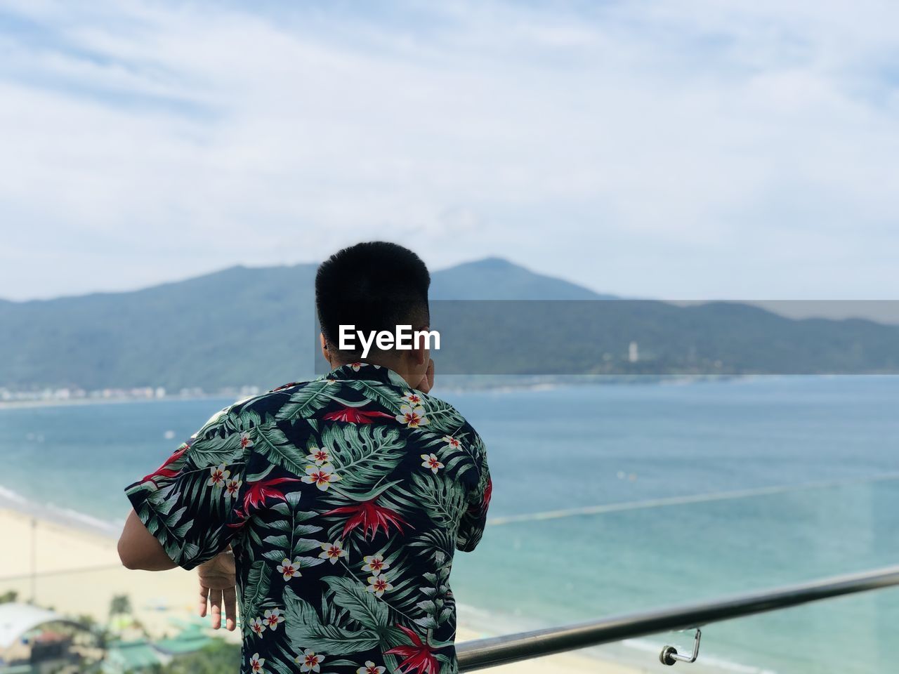 REAR VIEW OF MAN STANDING ON SEA AGAINST SKY